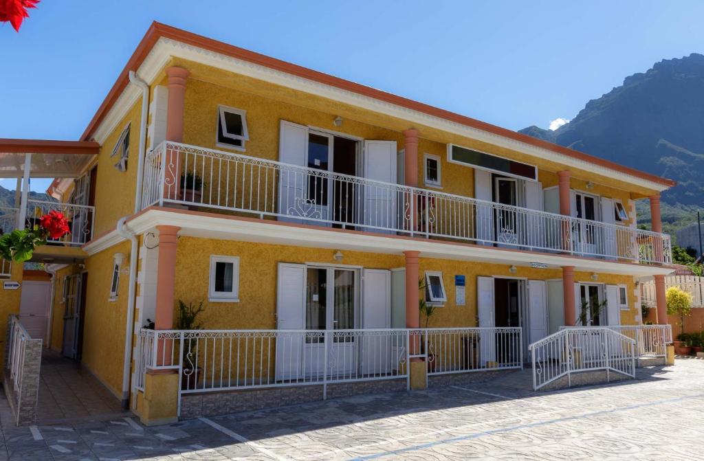 a yellow building with white balconies on a street at Otroiza Hotel in Cilaos