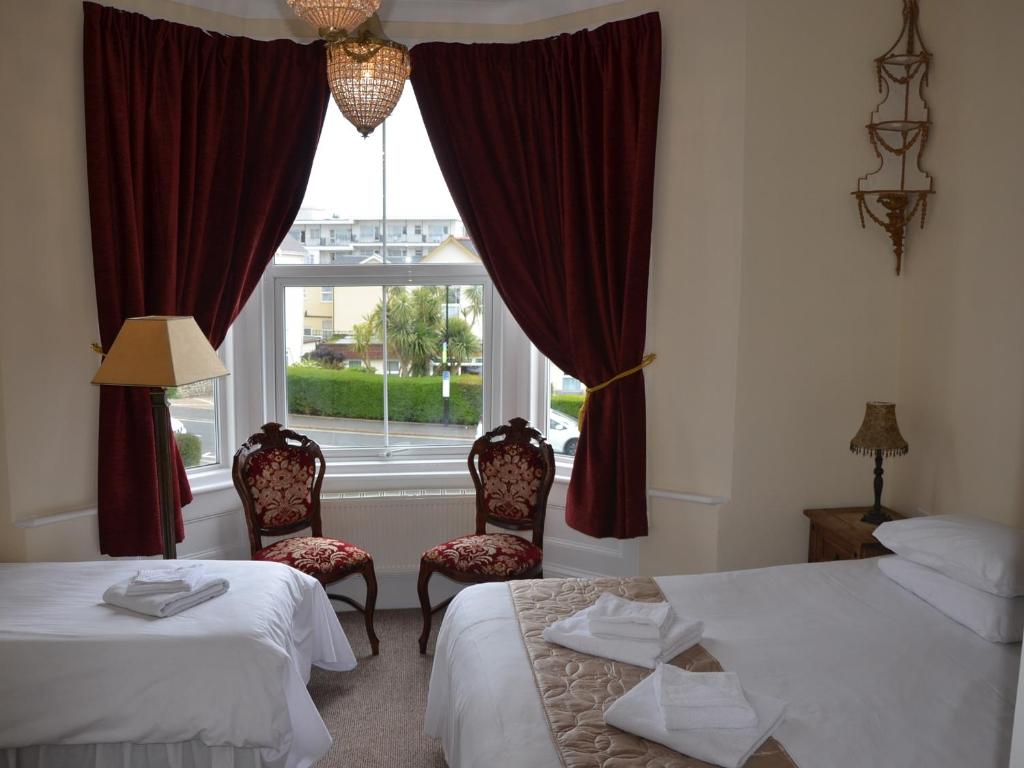 two beds in a room with two windows at Palmerston Grange in Shanklin
