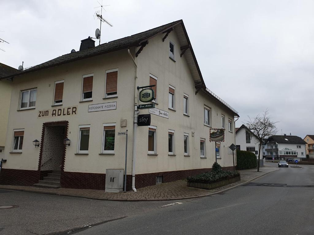 ein weißes Gebäude an der Ecke einer Straße in der Unterkunft Pension Zum Adler in Limbach