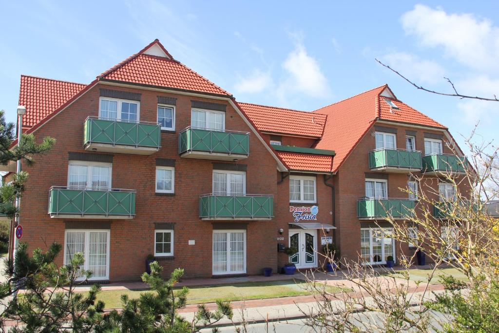 un edificio de ladrillo rojo con balcones verdes en Pension Frisia en Norddeich