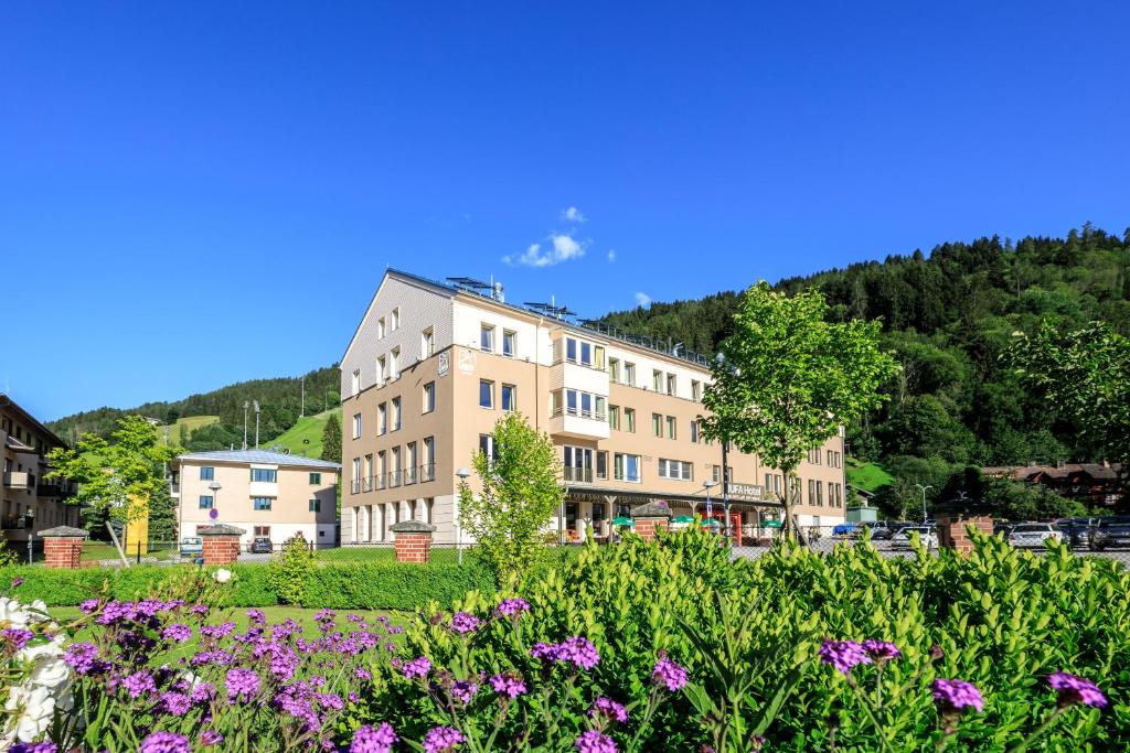 ein Gebäude mit lila Blumen davor in der Unterkunft JUFA Hotel Schladming in Schladming