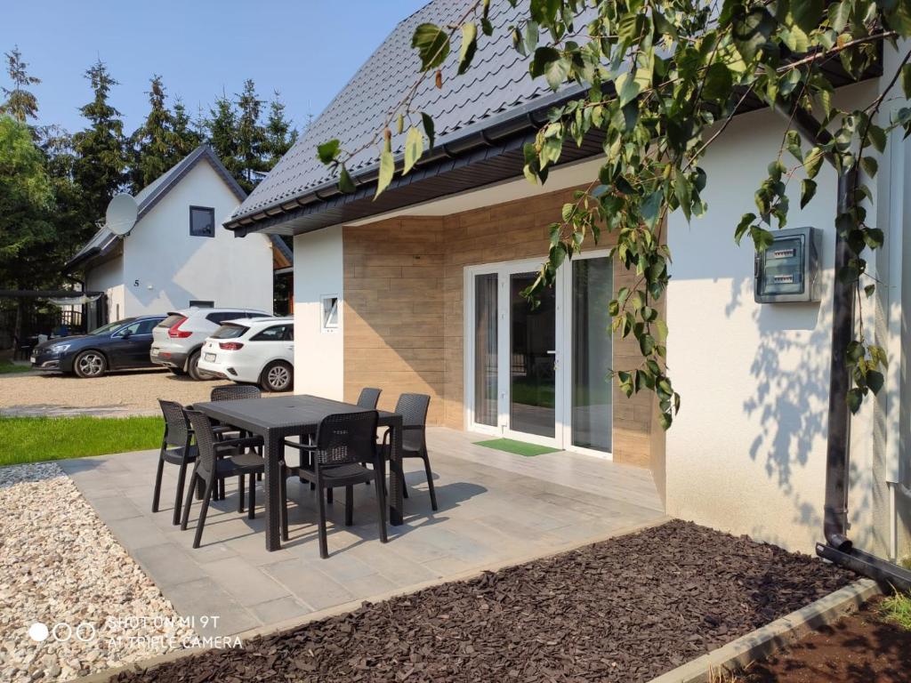 een terras met een tafel en stoelen voor een huis bij LEŚNA OSTOJA in Rewal
