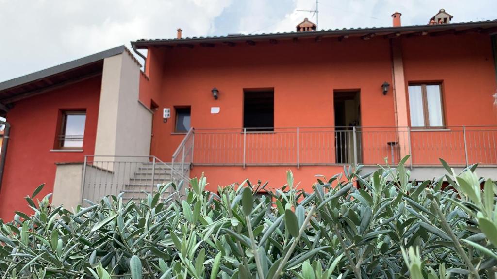 una casa roja con un seto delante de ella en BORGHETTO AIRPORT/HOSPITAL, en Bérgamo