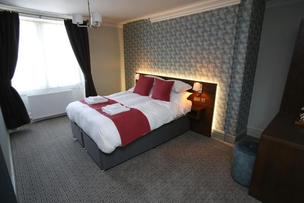 um quarto com uma cama grande e almofadas vermelhas em The Queens Head Hotel em Rothbury