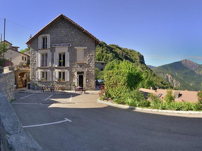 a building in a parking lot next to a mountain at Hostellerie de Rimplas in Rimplas