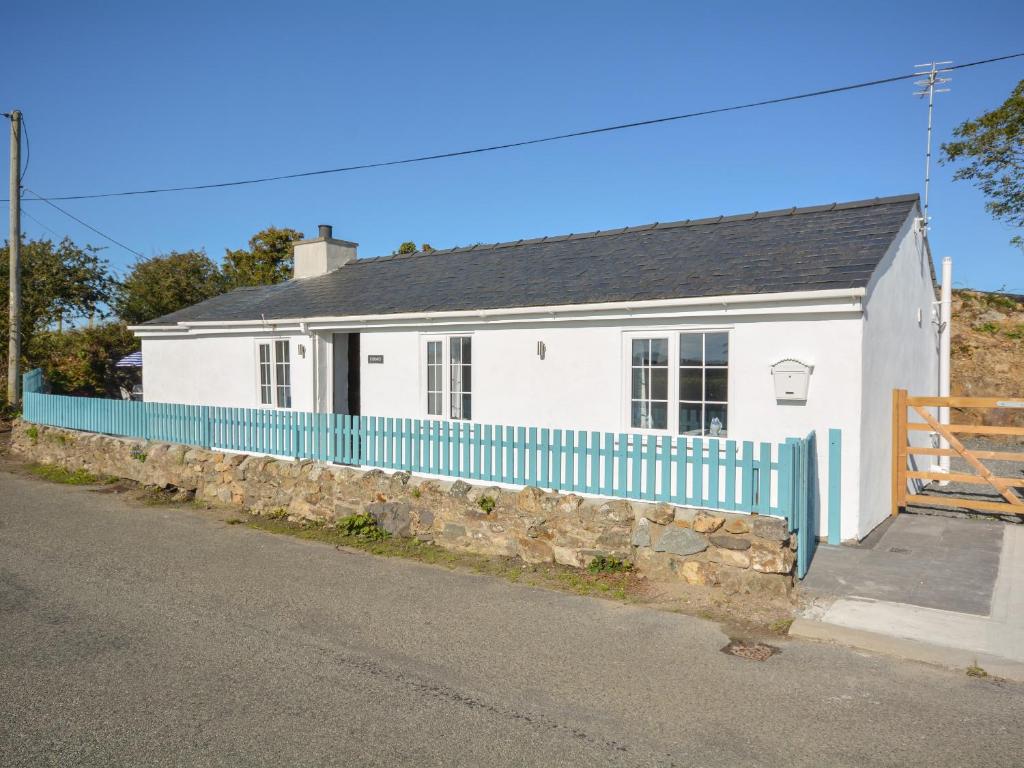 a white house with a blue fence on a street at Ffrwd in Holyhead