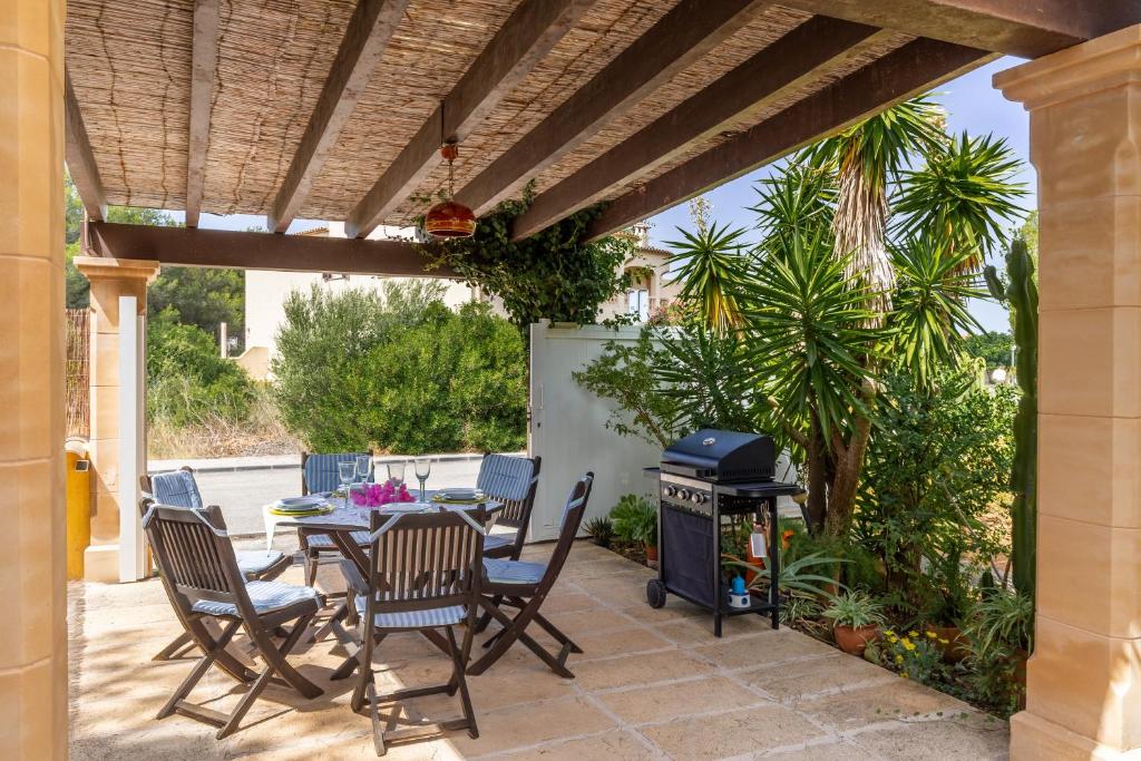 un patio con mesa, sillas y parrilla en S Estanyol, en Colonia de San Pedro