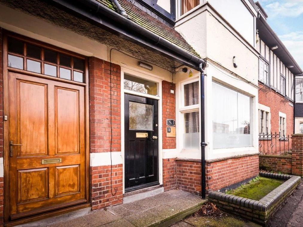 a brick house with a wooden door and a window at 1 Riverside Apartments in Norwich