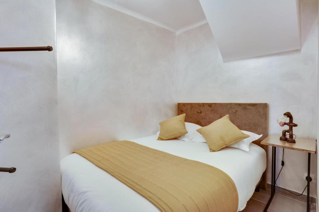 una camera da letto con un letto bianco con cuscini gialli di Roissy Appartements a Roissy en France