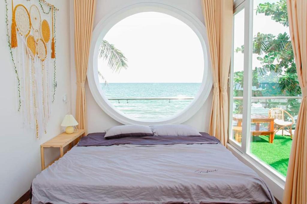 a bedroom with a bed and a large window at sunset beach house 3 in Phu Quoc