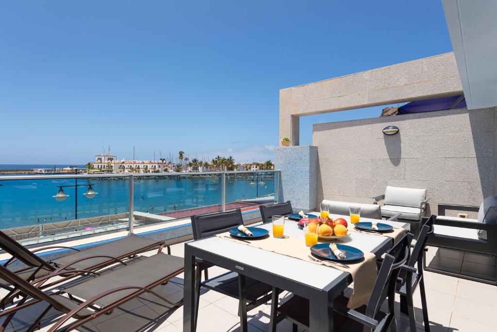 a table on a balcony with a view of the water at Amarre Bay in Puerto de Mogán