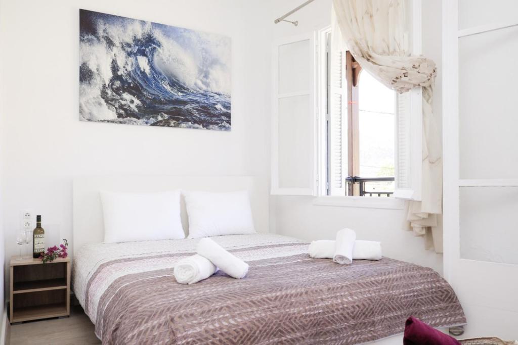 een witte slaapkamer met een bed met 2 kussens bij ilioditi in Skiathos-stad