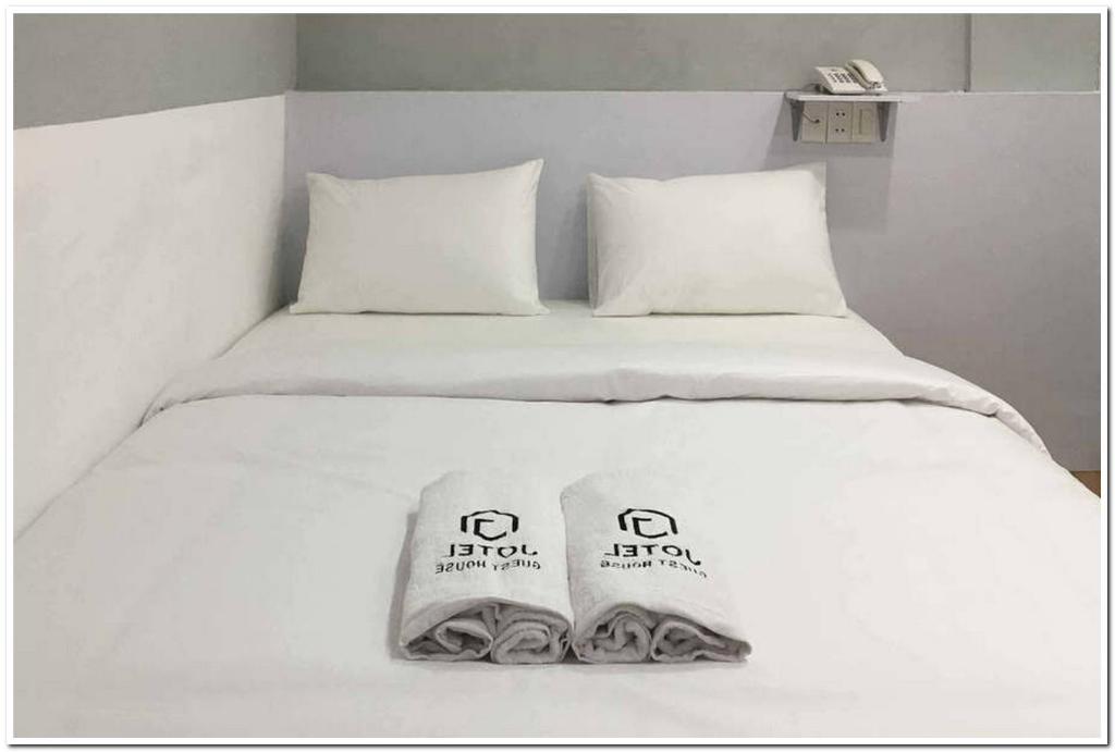 a white bed with two towels on top of it at Jotel Guest House Mitra RedDoorz in Pulauberayan