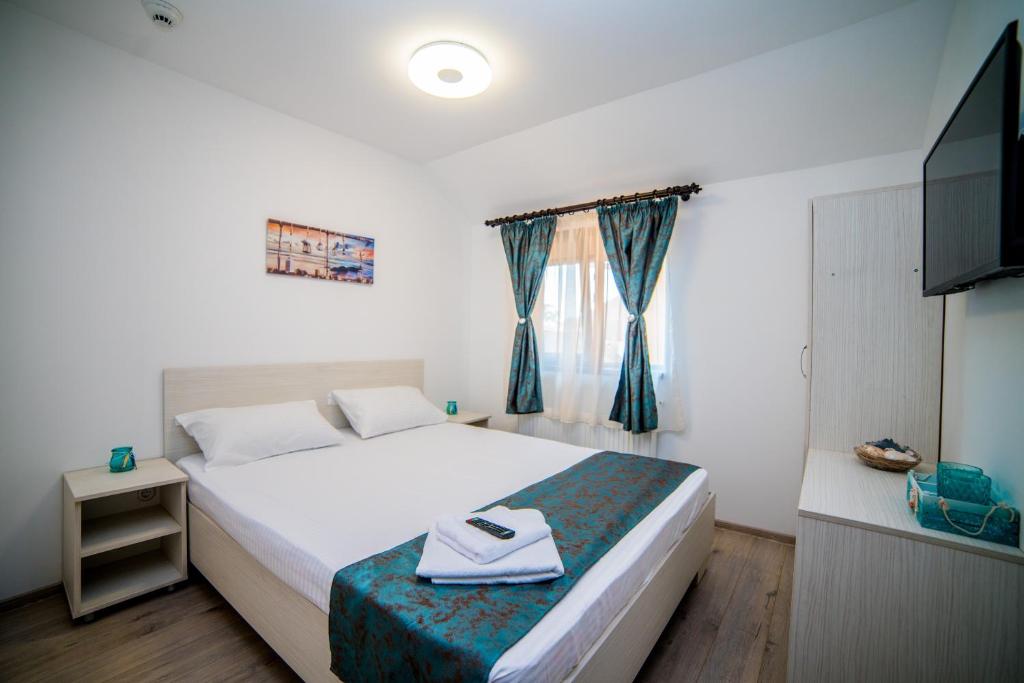 a bedroom with a white bed and a television at Vila Anastasia in Mangalia