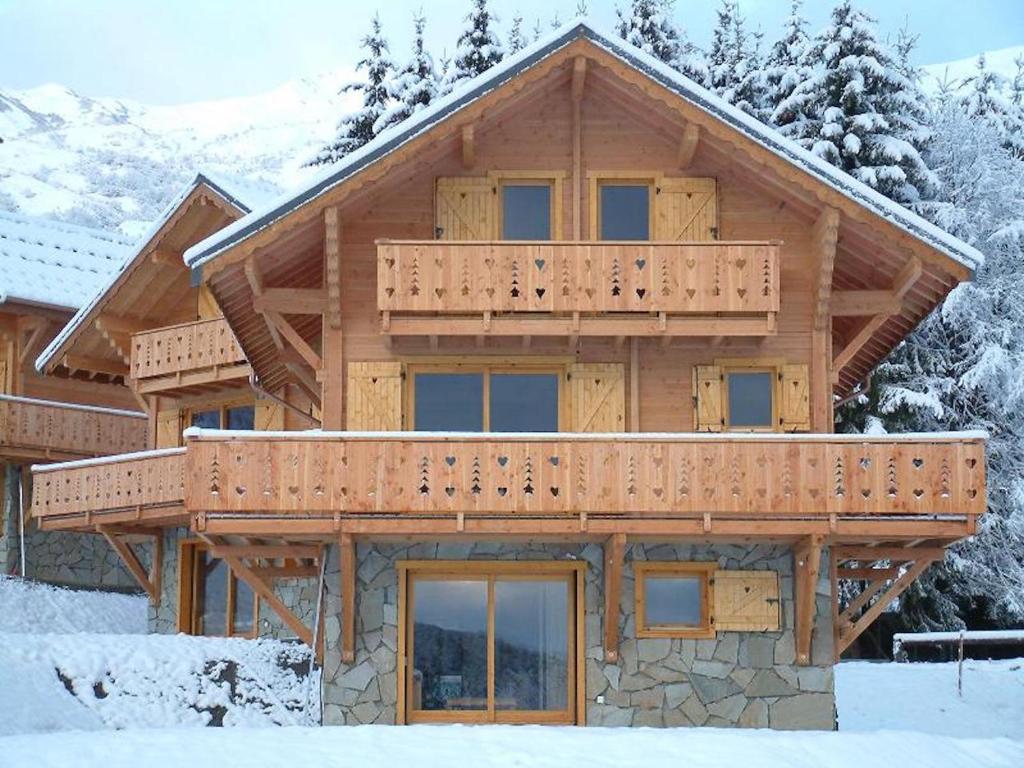 Cette grande maison en bois dispose d'un balcon dans la neige. dans l'établissement Résidence Sourires et Vacances, à Saint-Pancrace