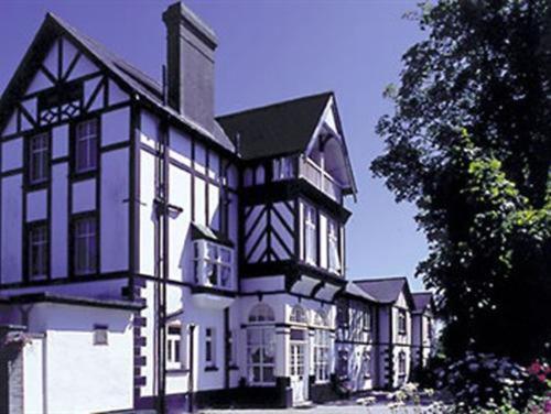 a large white and black building with a tree at Rosemullion Hotel in Falmouth