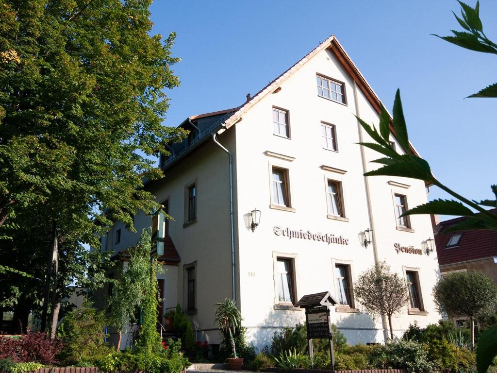 un bâtiment blanc avec un panneau devant lui dans l'établissement Pension Schmiedeschänke, à Dresde
