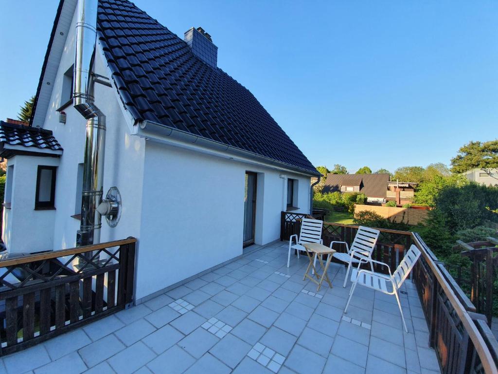 a balcony with white chairs and a house at @ home Zimmervermietung in Norderstedt