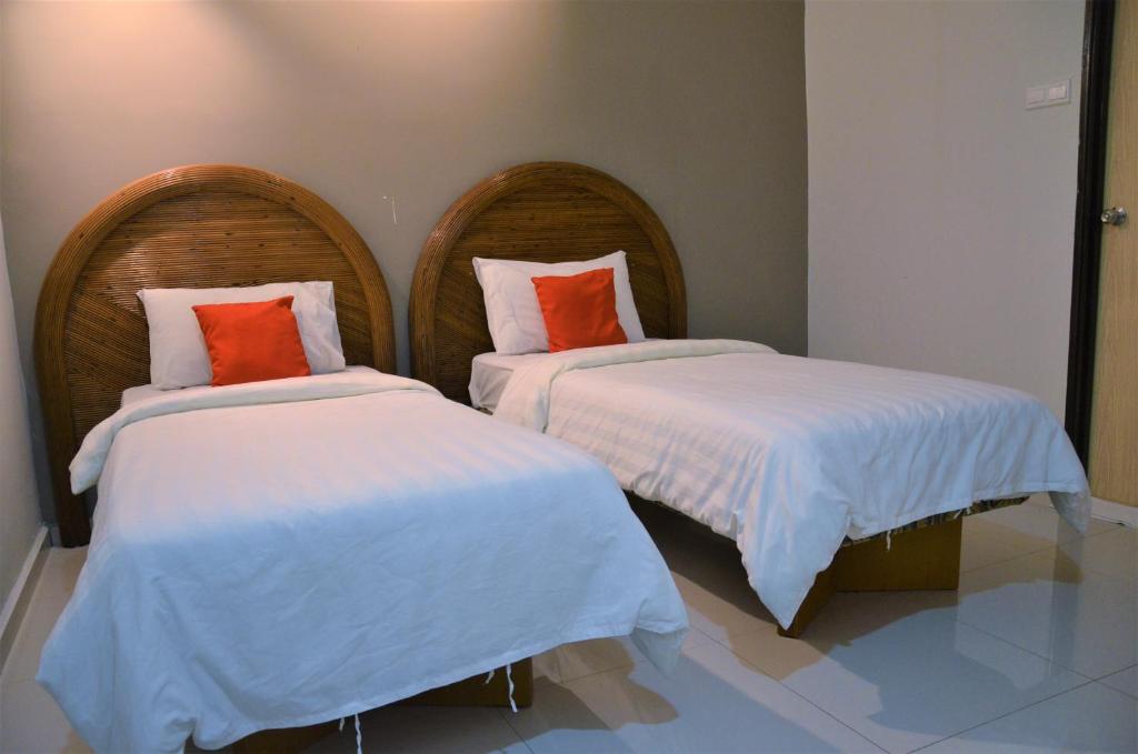 Senrose Hotel Kuantan في كُوانتان: سريرين مع وسائد بيضاء برتقالية في الغرفة