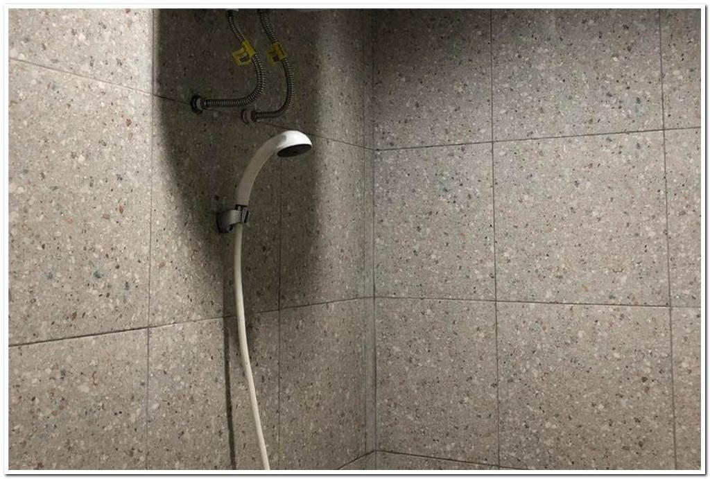 a shower with a hose attached to a wall at RedDoorz near RS Adam Malik Medan 2 in Sunggal