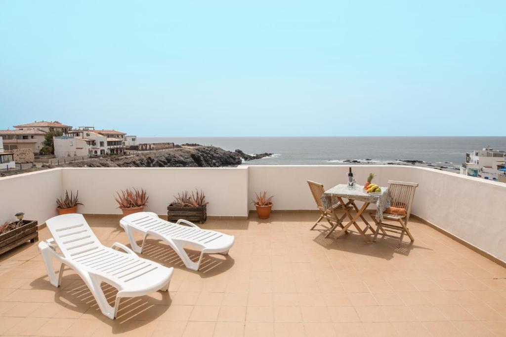 a balcony with a table and chairs and the ocean at Apartamento Benitez Umpierrez in El Cotillo