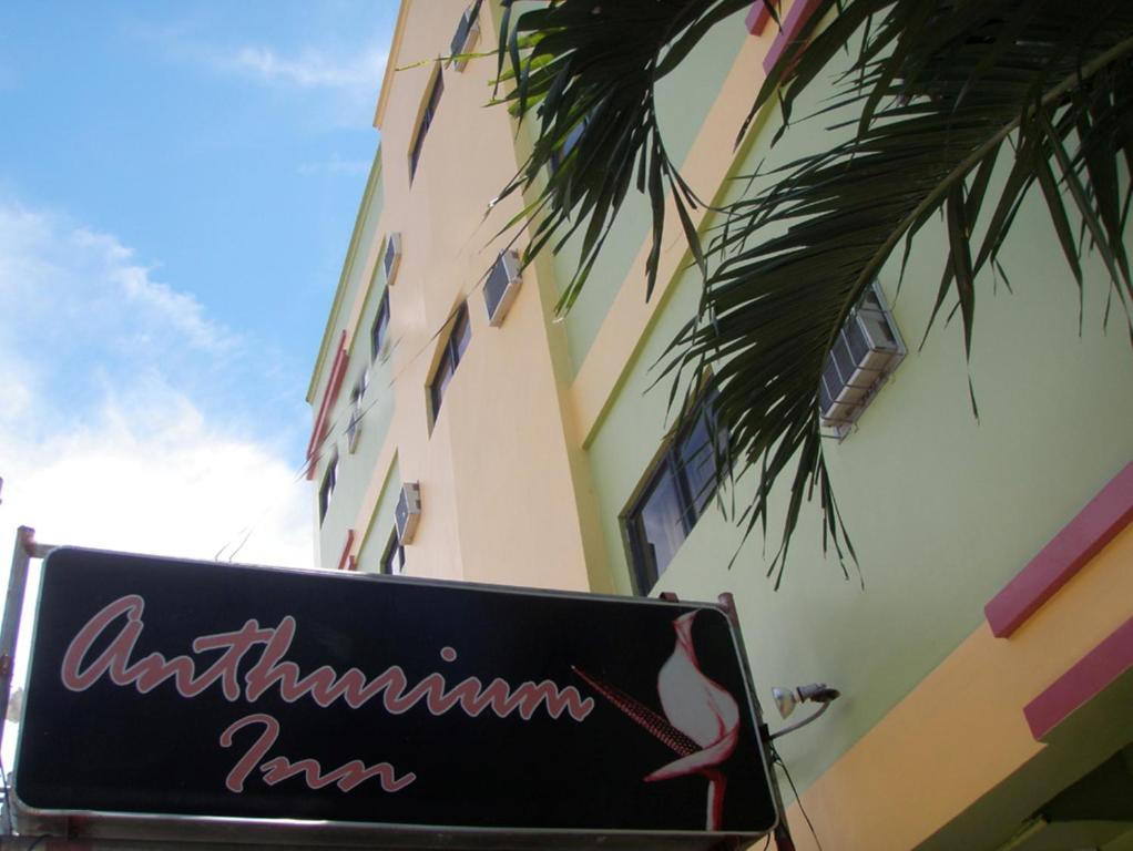 a sign in front of a building with a palm tree at Anthurium Inn in Mactan