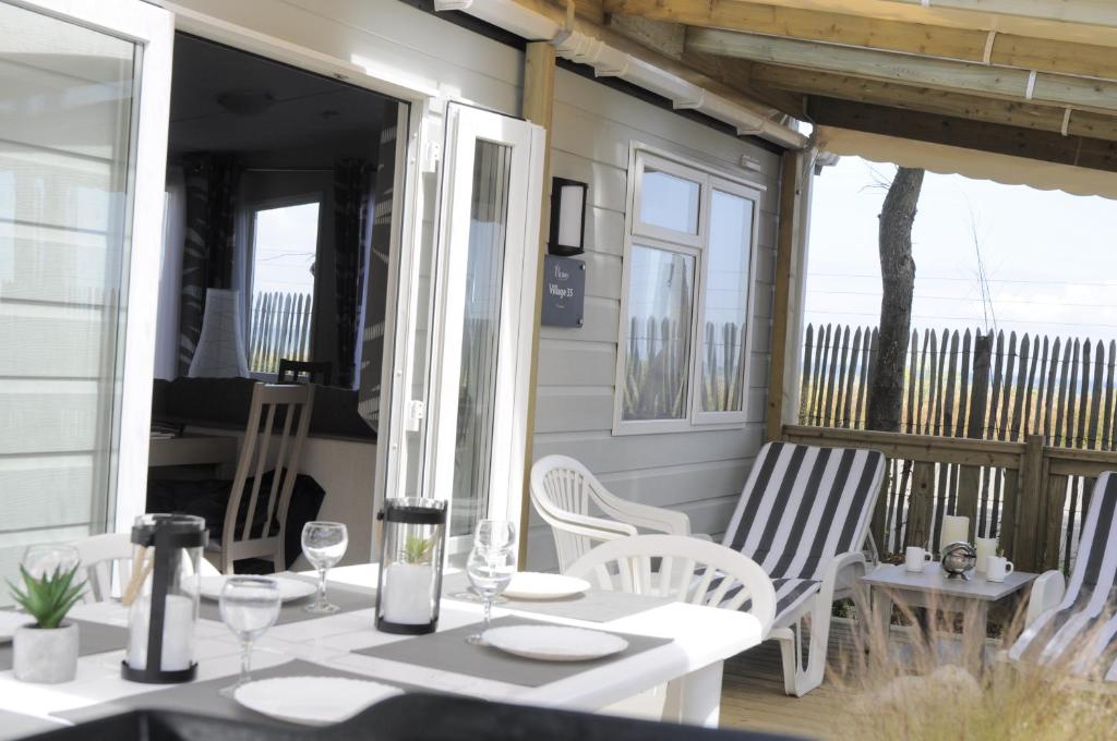 a porch with white chairs and a table with glasses at Mobilhome Victory 56 in Quiberon