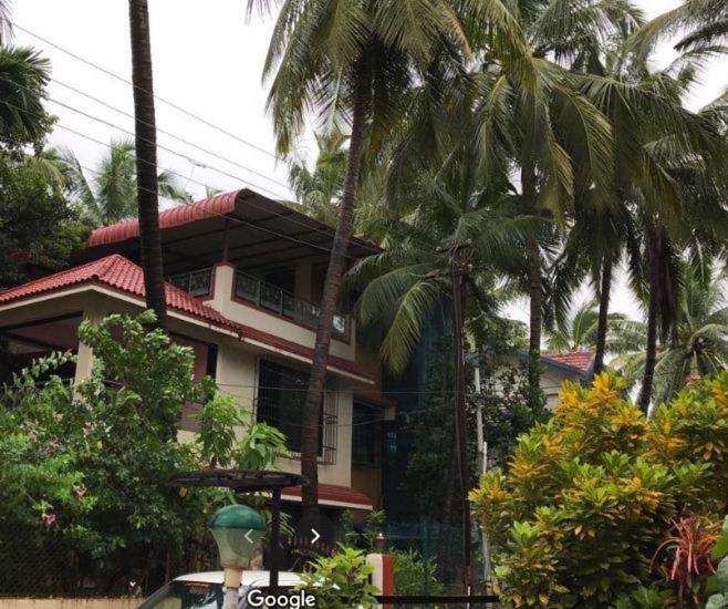 a house with palm trees in front of it at Swapnapurti Bungalow 2BHK in Alibaug