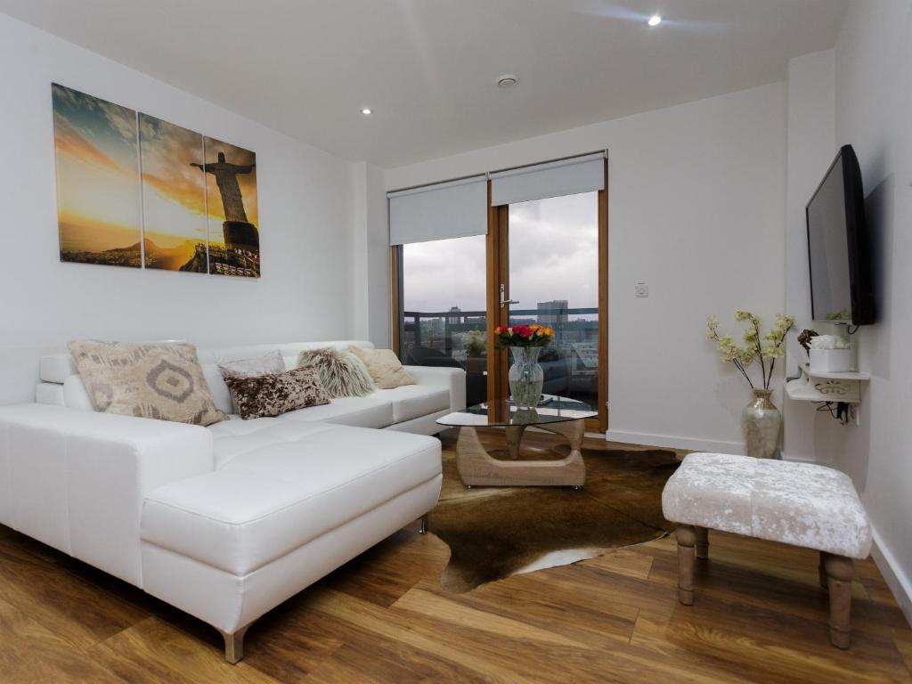 a white living room with a white couch and a tv at Live in Leeds Sky Penthouse in Leeds