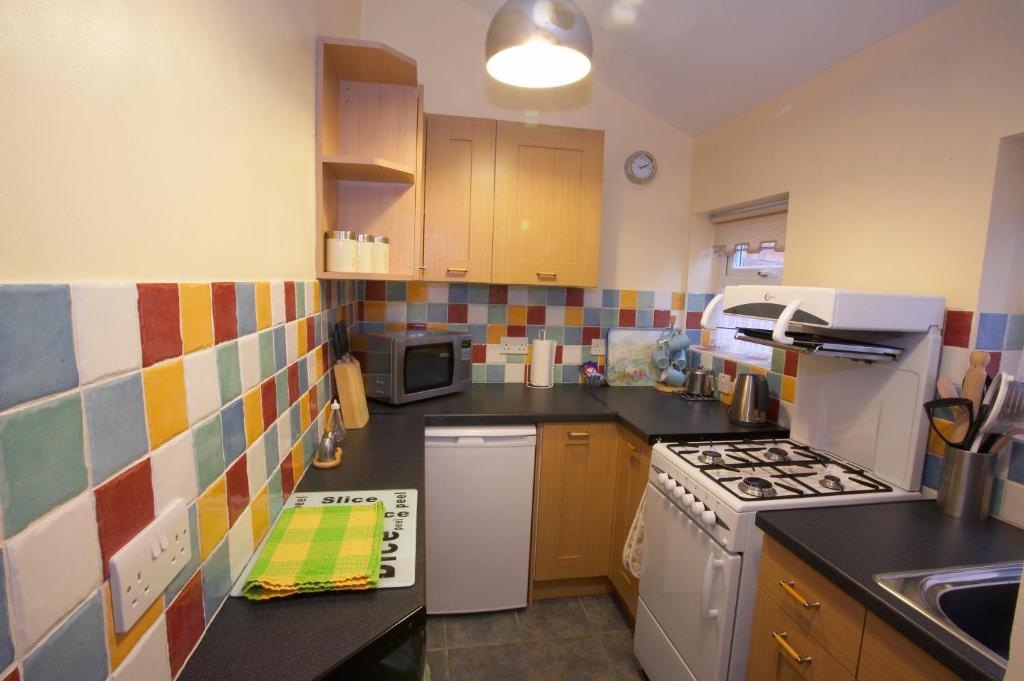 a small kitchen with a stove and a sink at Saltburn Holidays Primrose Cottage in Guisborough