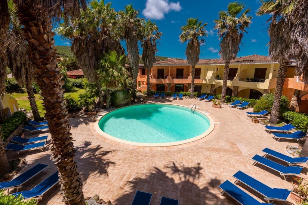 an outdoor swimming pool with lounge chairs and palm trees at Palau Green Village in Palau