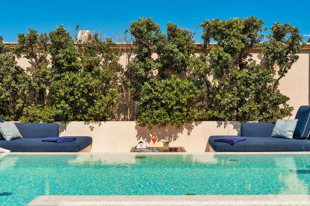 a swimming pool with two blue couches and trees at Palazzo del Corso – Boutique Hotel in Gallipoli