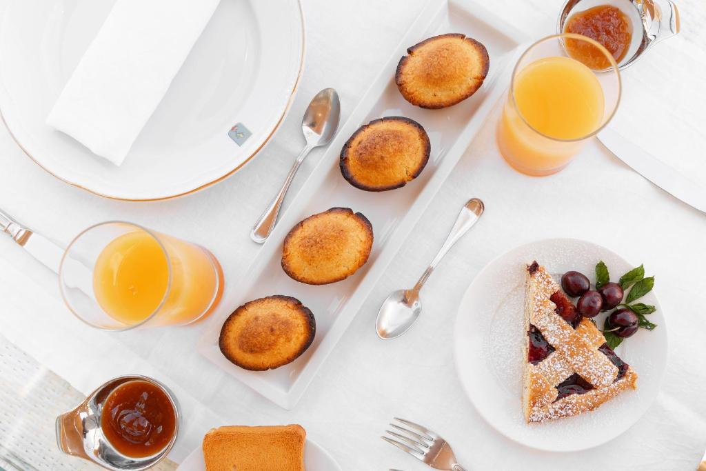 a table with plates of food and glasses of orange juice at Palazzo del Corso – Boutique Hotel in Gallipoli