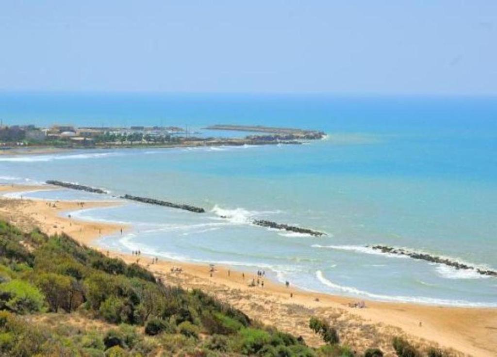 a beach with people walking on the sand and the water at Giafra Luxury Rooms in Agrigento