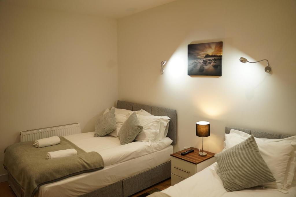 um quarto com duas camas e um candeeiro sobre uma mesa em Serviced Property Plymouth em Plymouth