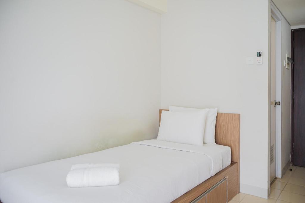 a white bed with white sheets and pillows on it at Chic Studio at Serpong Green View Apartment By Travelio in Ciater-hilir