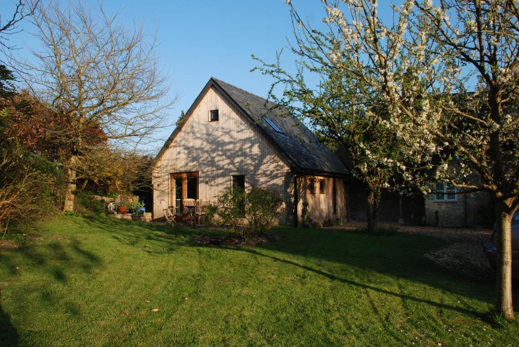 un granero blanco con techo negro en un patio en Garden Studio Spring Cottage en Teffont Magna