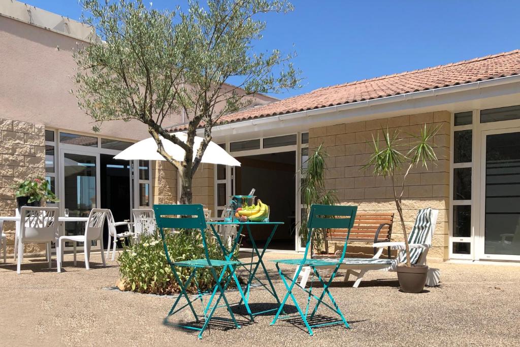 un groupe de chaises et une table devant une maison dans l'établissement Patio Parc Résidence, à Argenton lʼÉglise