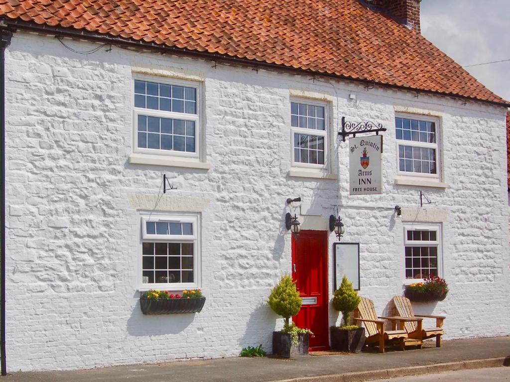 a white building with a red door at St Quintin Arms in Harpham