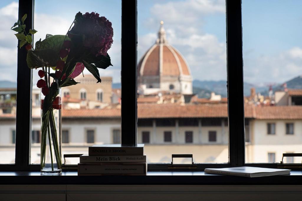 een vaas met bloemen en boeken op een vensterbank bij Premiere Apartments Ponte Vecchio in Florence