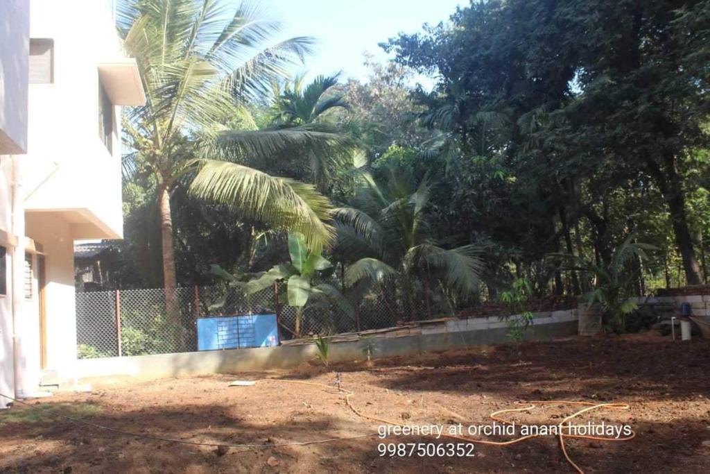 a fence with palm trees in front of a house at Orchid Anant Holidays in Alibaug