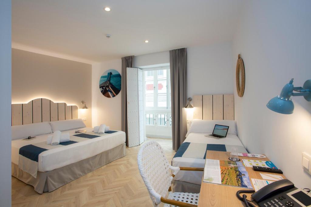 a bedroom with two beds and a table with a desk at Casual con Duende Cadiz in Cádiz