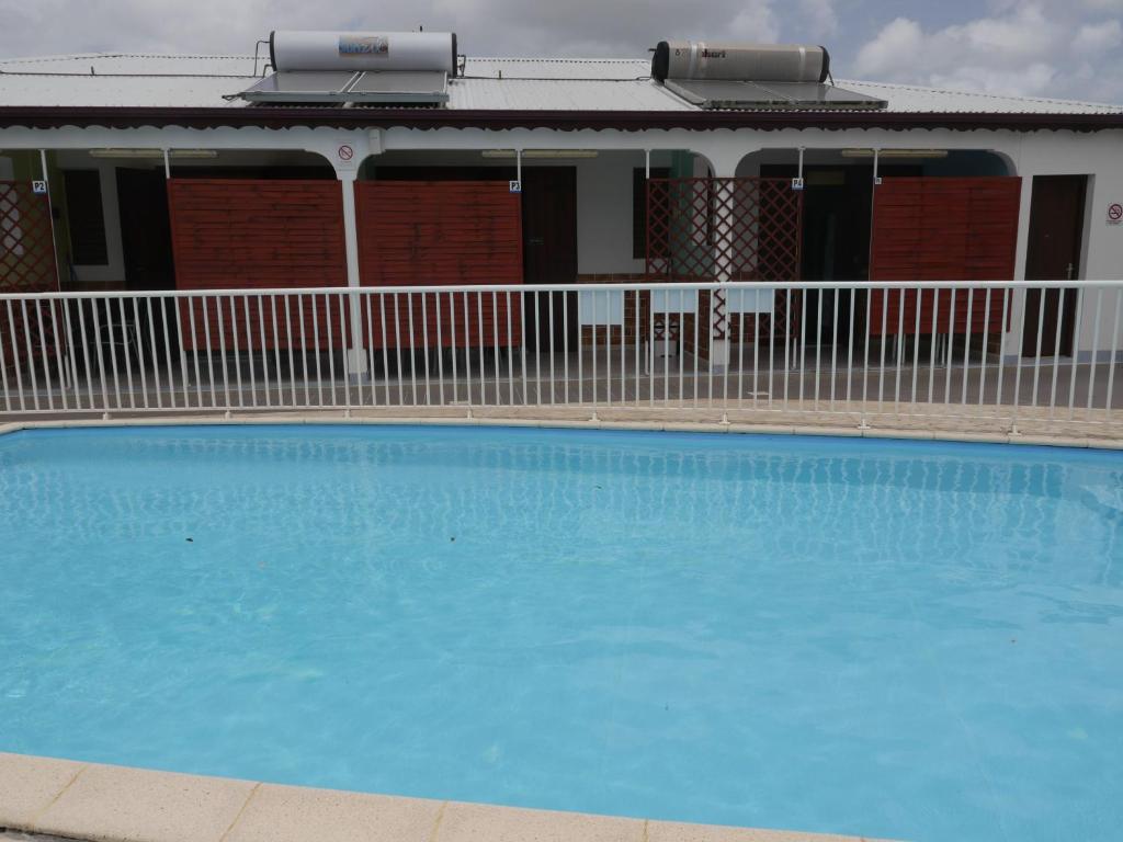 a large blue swimming pool in front of a house at Les Gîtes De L'union in Les Abymes