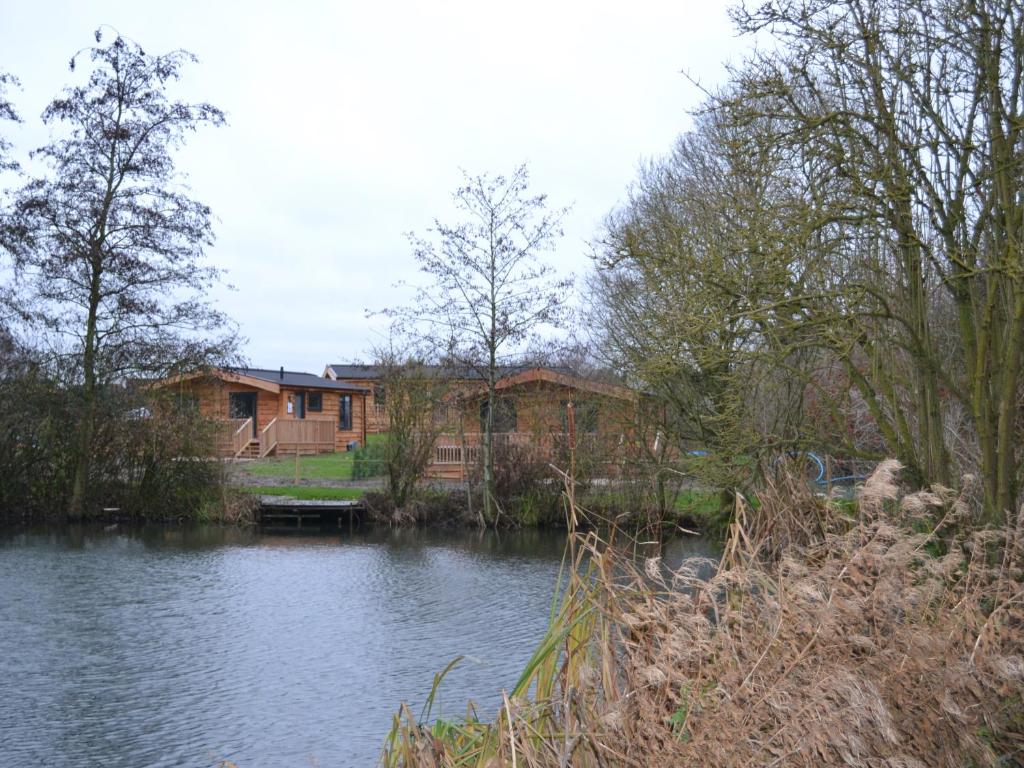 a house next to a river with a building at The Chiltern Lodges at Upper Farm Henton in Chinnor