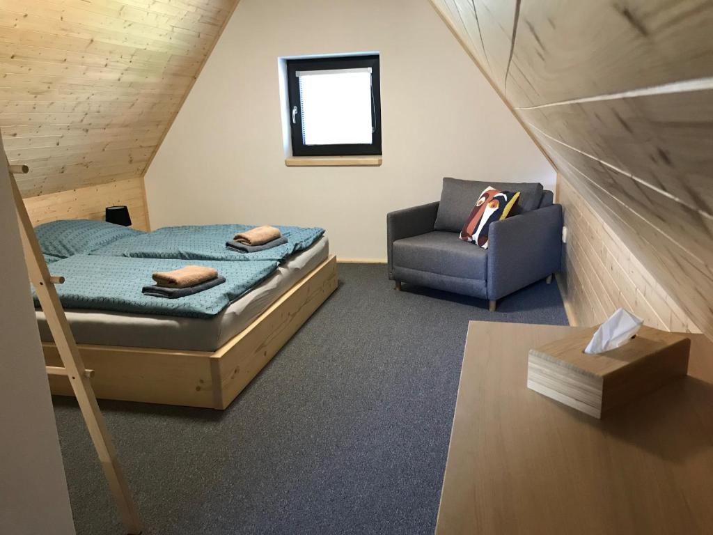 een slaapkamer met een bed en een stoel in een kamer bij Chata Bellis in Černá v Pošumaví