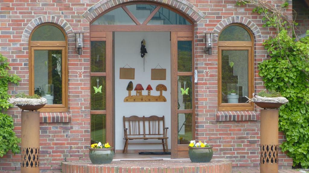 uma porta da frente de um edifício de tijolos com um banco em Hillrichshof em Neuharlingersiel