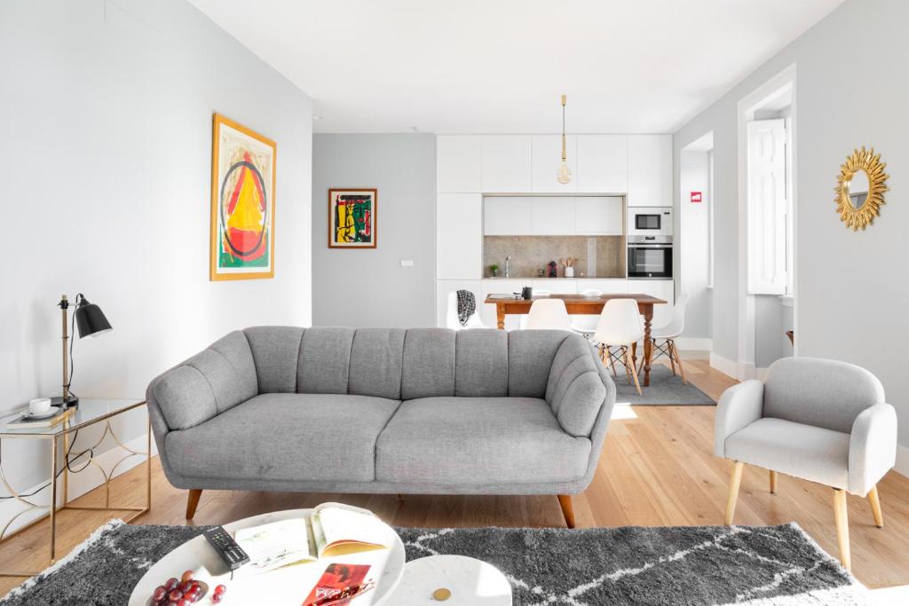 a living room with a gray couch and a kitchen at JOIVY Marvelous 3-bed home with astonishing view and terrace, nearby St George Castle in Lisbon