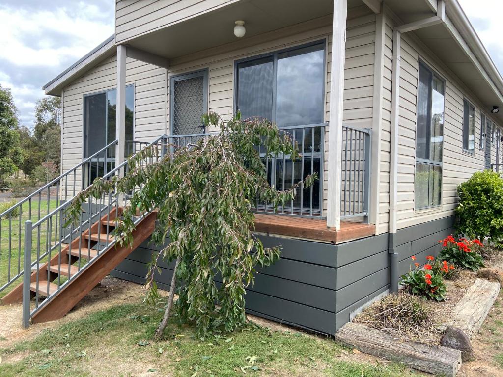 ein Haus mit einer Terrasse mit einem Baum in der Unterkunft Yeoy's Cabin in Tallarook