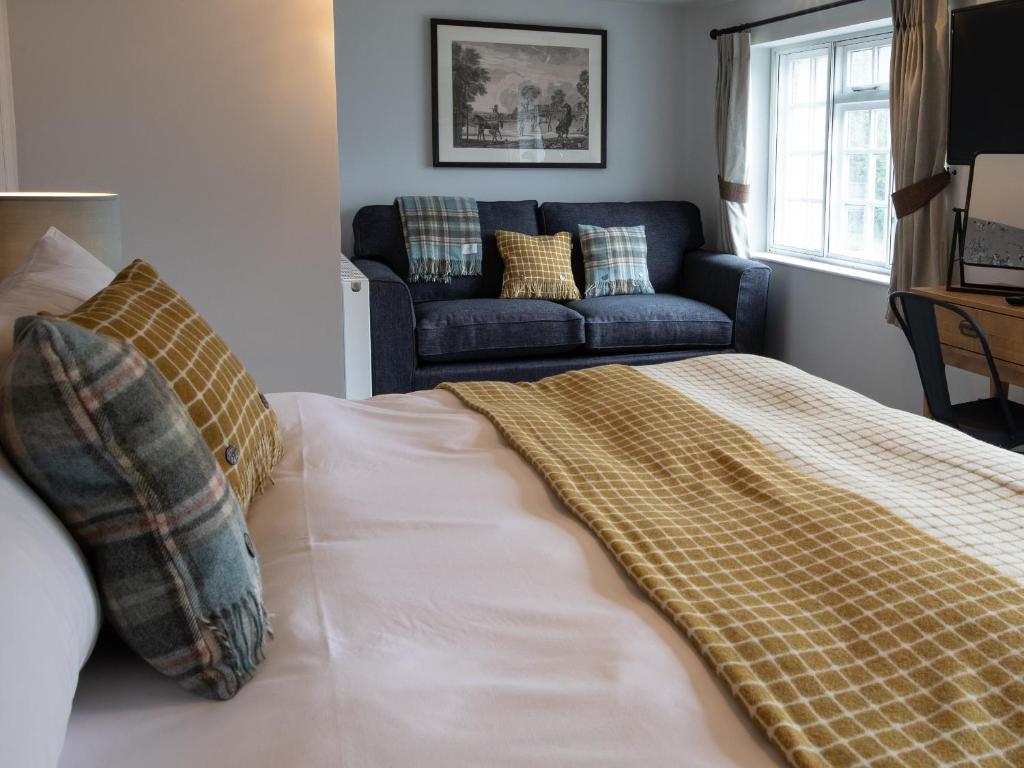 a bedroom with a bed with a couch in the background at The Exeter Inn in Bampton