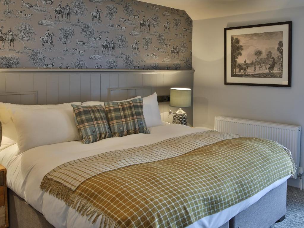 a bedroom with a bed with a plaid blanket at The Exeter Inn in Bampton